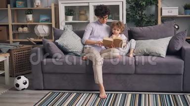 一位年轻的女士和她的儿子一<strong>起坐</strong>在工作室公寓的沙发上看书